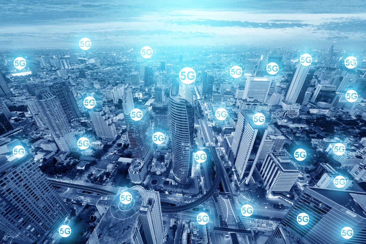Cityscape view overlaid with multiple glowing "5G" icons, illustrating the widespread availability of next-generation mobile network coverage in an urban environment.
